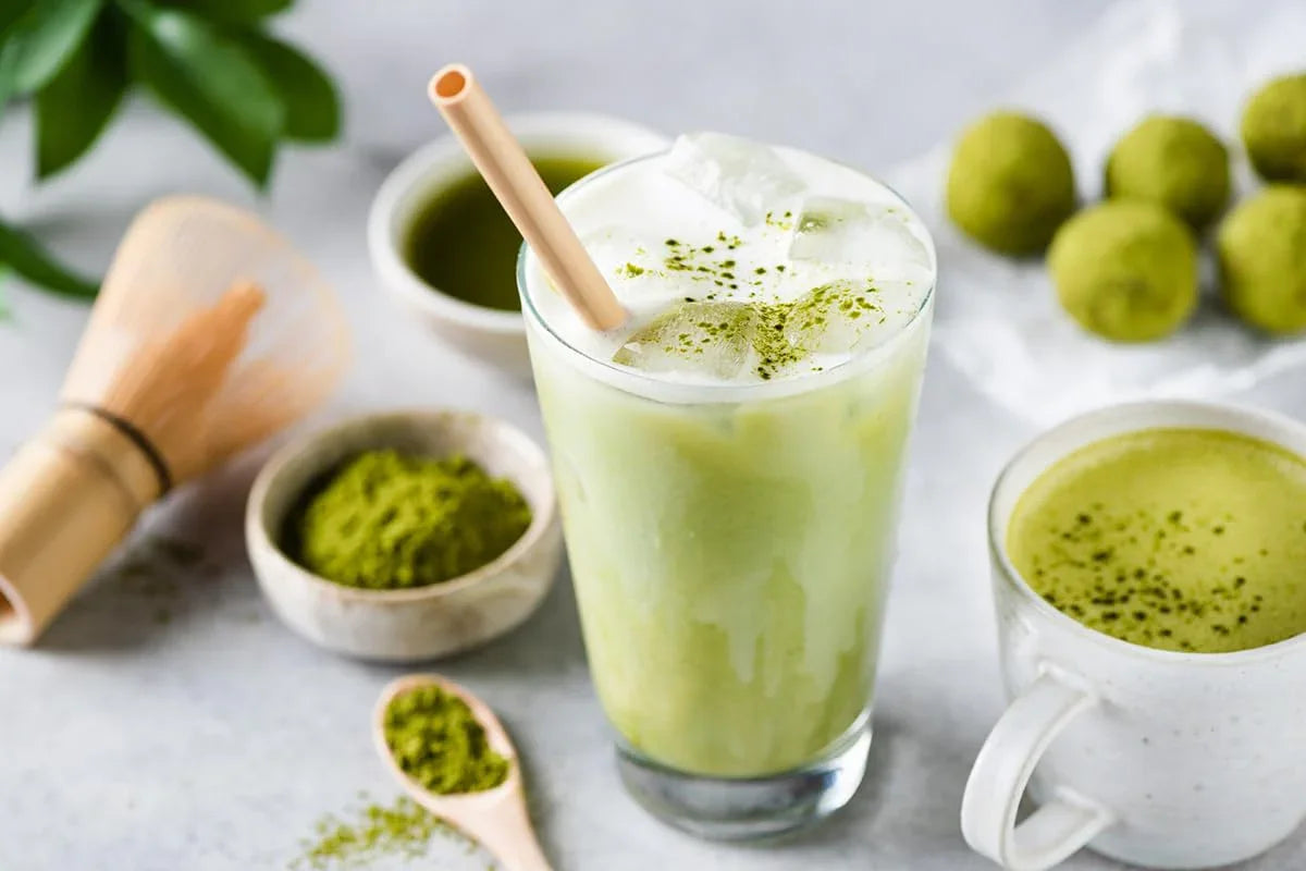 Erfrischender Matcha Latte mit Eiswürfeln, Matchapulver und Matcha-Trüffeln auf einem Tisch